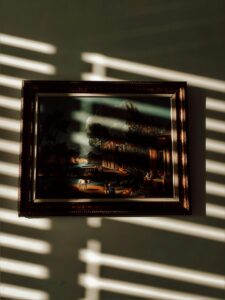 Harsh shadows from blinds obscuring a framed artwork